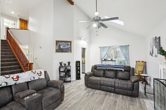 living room featuring ceiling fan, a skylight, light hardwood / wood-style floors, and high vaulted ceiling