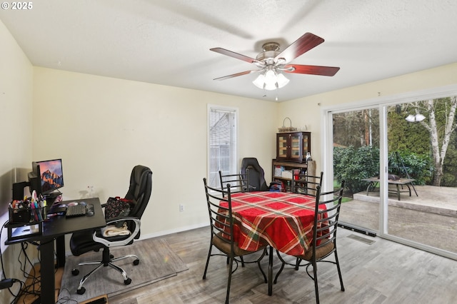 dining area with ceiling fan, wood-type flooring, and a textured ceiling