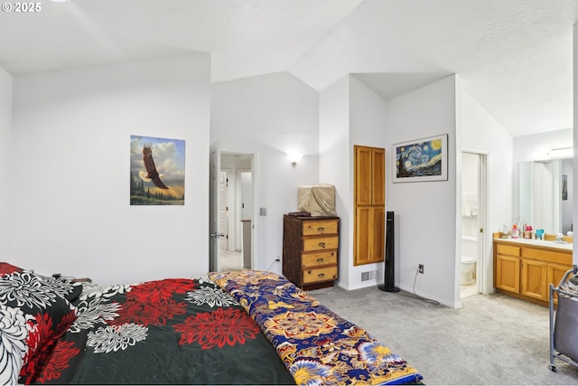 carpeted bedroom with vaulted ceiling and ensuite bathroom