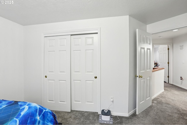 bedroom featuring a closet, a textured ceiling, and dark colored carpet