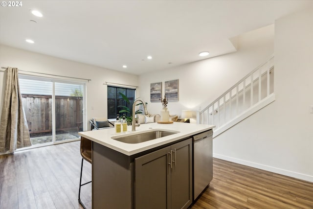 kitchen with a kitchen island with sink, sink, dishwasher, and hardwood / wood-style flooring