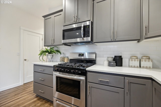 kitchen with decorative backsplash, gray cabinets, light hardwood / wood-style floors, and stainless steel appliances