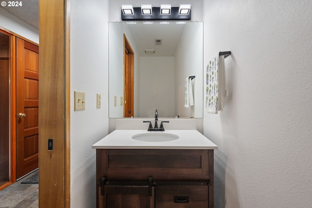 bedroom featuring a barn door, a textured ceiling, baseboards, and wood finished floors