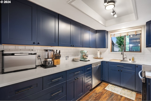 kitchen featuring a sink, light countertops, appliances with stainless steel finishes, and a raised ceiling