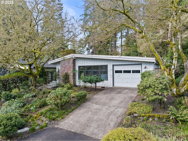 view of front facade featuring a chimney, driveway, and an attached garage