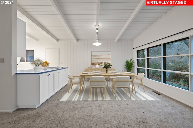 unfurnished dining area with baseboards, carpet flooring, visible vents, and beamed ceiling