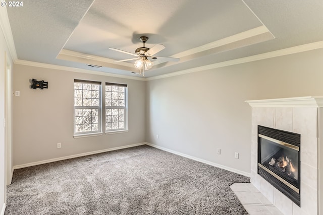 unfurnished living room featuring a tile fireplace, ceiling fan, a raised ceiling, crown molding, and light colored carpet