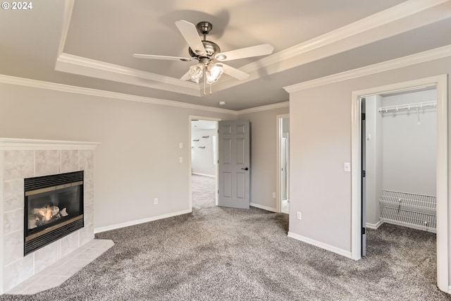 unfurnished living room featuring carpet flooring, ornamental molding, a tile fireplace, and a tray ceiling