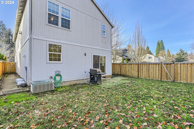 back of property with a yard and central AC