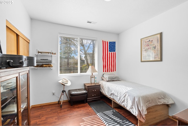 bedroom featuring baseboards, visible vents, and wood finished floors