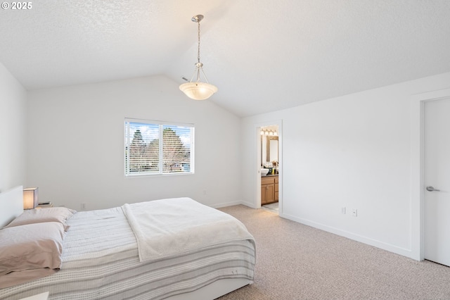 bedroom with a textured ceiling, light carpet, baseboards, vaulted ceiling, and ensuite bath