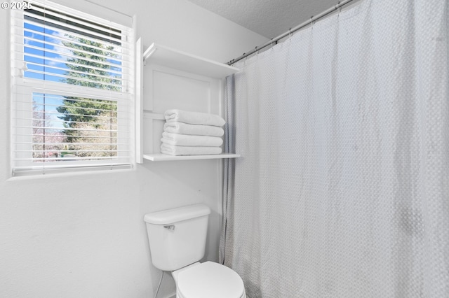 bathroom with a shower with curtain, a textured ceiling, and toilet