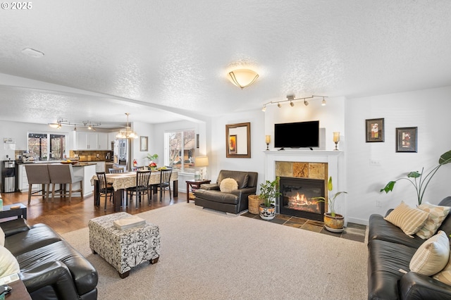 living area with plenty of natural light, dark wood-type flooring, a textured ceiling, and a tile fireplace