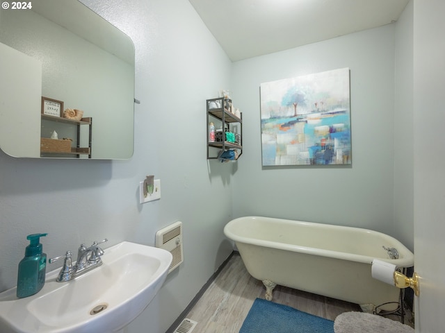 bathroom with sink, a tub to relax in, and wood-type flooring