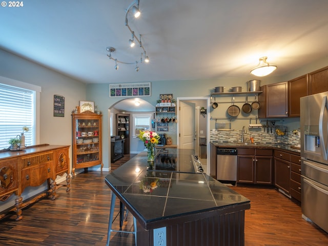 kitchen with stainless steel appliances, dark hardwood / wood-style flooring, backsplash, and a kitchen island