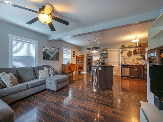 living room with dark wood-type flooring, ceiling fan, and beam ceiling