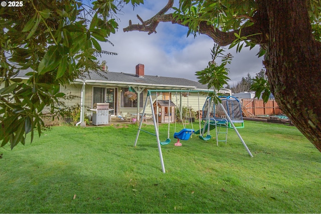 exterior space with a trampoline, a playground, and a lawn