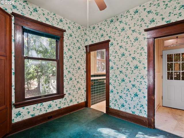 unfurnished room with ceiling fan and dark colored carpet