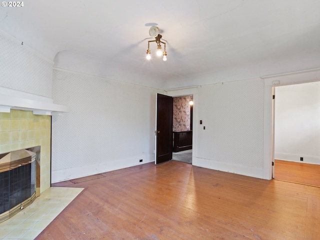 unfurnished living room with light wood-type flooring and a tile fireplace