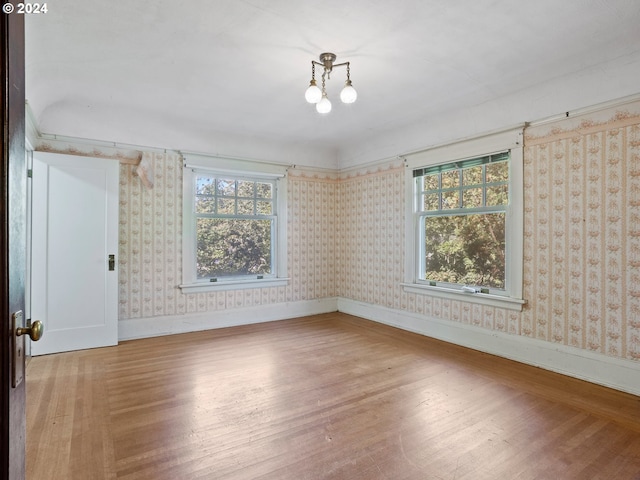 spare room featuring a chandelier and light wood-type flooring