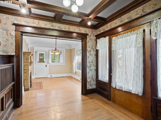 entryway featuring light wood-type flooring, coffered ceiling, beam ceiling, a notable chandelier, and ornamental molding