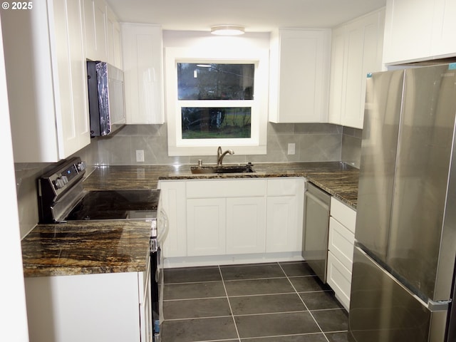 kitchen with white cabinets, dark tile patterned flooring, sink, and stainless steel appliances