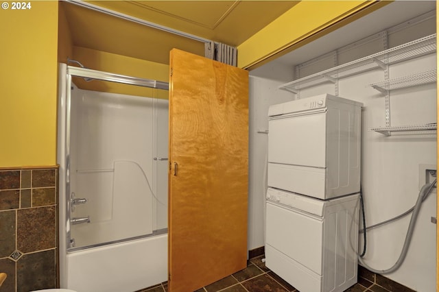 clothes washing area featuring stacked washing maching and dryer and dark tile flooring