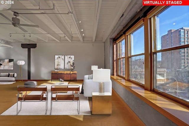 dining space featuring hardwood / wood-style floors, ceiling fan, a wood stove, beamed ceiling, and track lighting