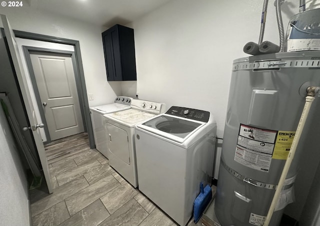 laundry area with strapped water heater, washer and clothes dryer, cabinet space, and wood tiled floor