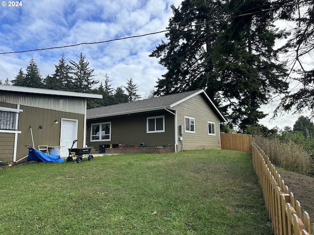 rear view of house featuring fence and a lawn