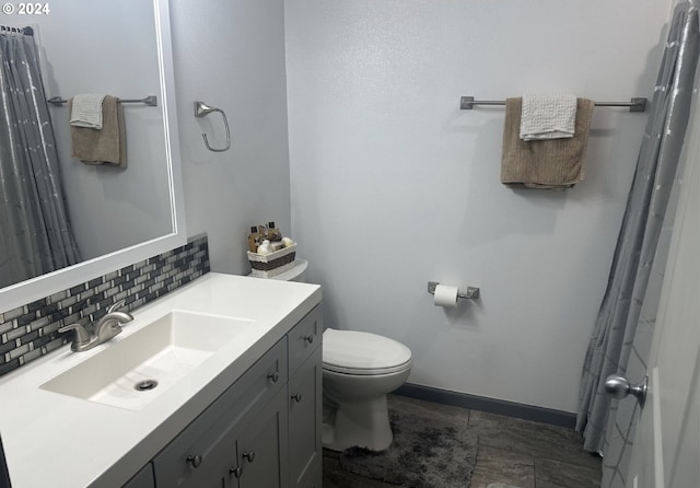 bathroom featuring baseboards, backsplash, toilet, and vanity