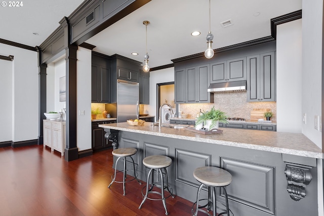 kitchen with ornamental molding, a kitchen bar, pendant lighting, and sink