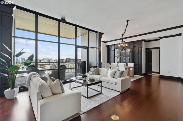 living room with crown molding, dark hardwood / wood-style flooring, expansive windows, and a notable chandelier