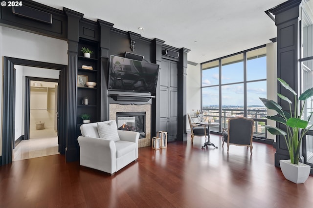 living room featuring a multi sided fireplace, built in features, expansive windows, and dark hardwood / wood-style flooring