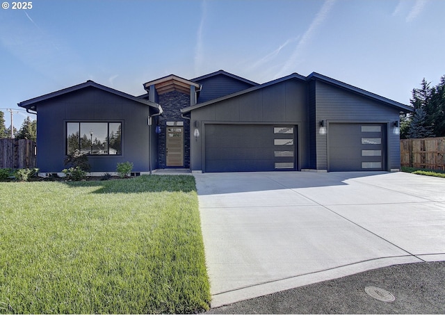 view of front of property with concrete driveway, an attached garage, board and batten siding, fence, and a front lawn