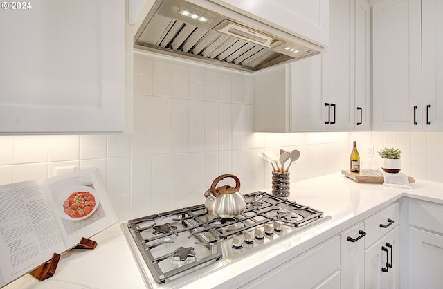 kitchen with white cabinets, premium range hood, stainless steel gas cooktop, and decorative backsplash