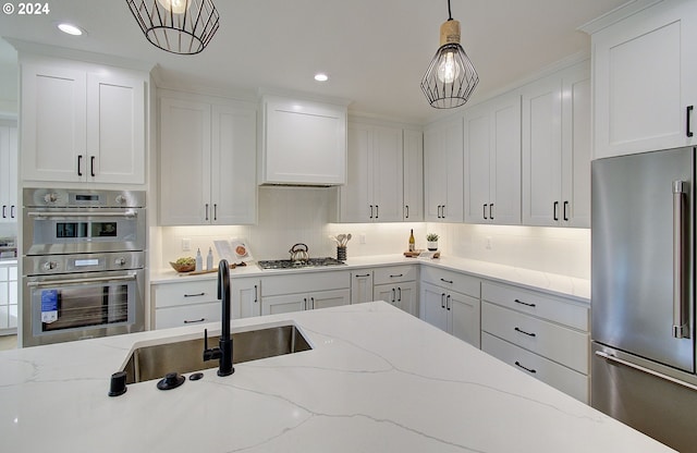 kitchen featuring appliances with stainless steel finishes, a sink, white cabinets, and tasteful backsplash