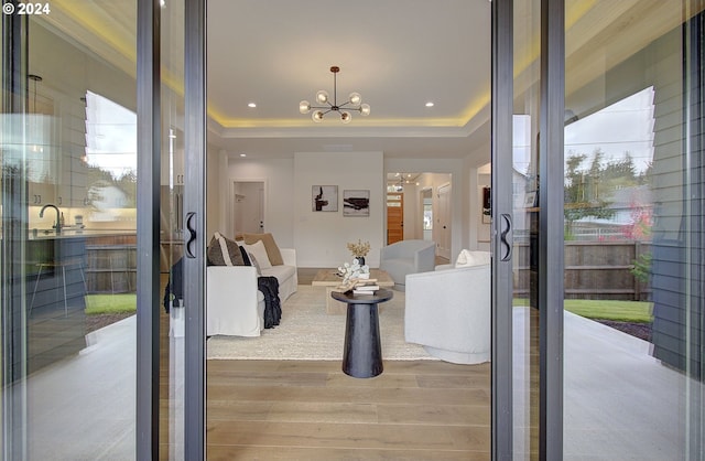 entryway with a tray ceiling, a chandelier, wood finished floors, and recessed lighting