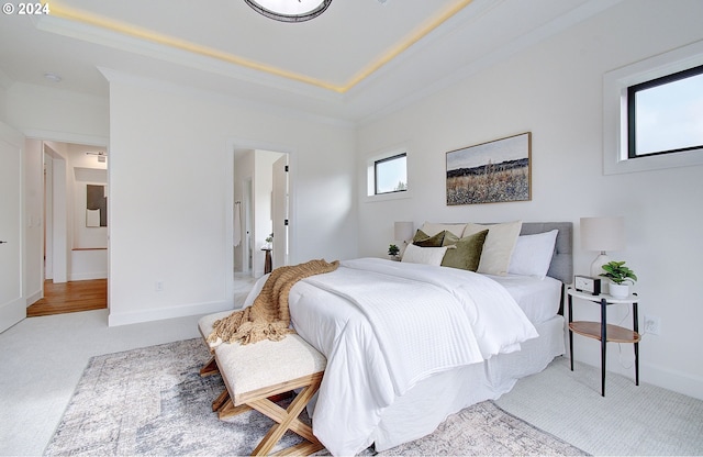 bedroom featuring a tray ceiling, carpet, and baseboards