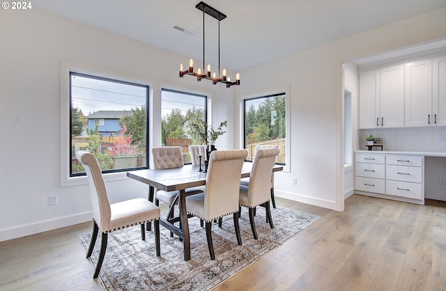 dining room with visible vents, baseboards, light wood-style flooring, and a notable chandelier