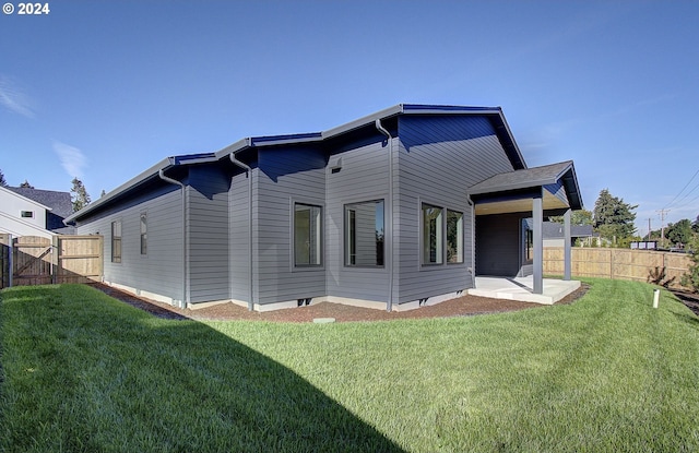 rear view of house featuring a yard, fence, and a patio