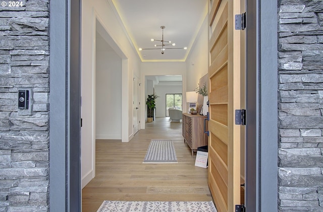 corridor featuring ornamental molding, a chandelier, and light hardwood / wood-style flooring