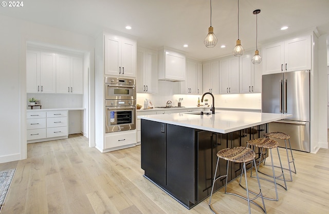 kitchen with tasteful backsplash, white cabinets, appliances with stainless steel finishes, light countertops, and a sink