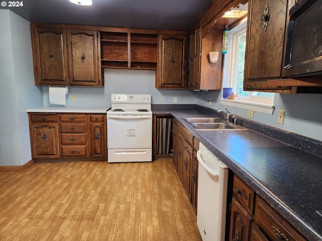 kitchen with dark brown cabinets, sink, white appliances, and light wood-type flooring