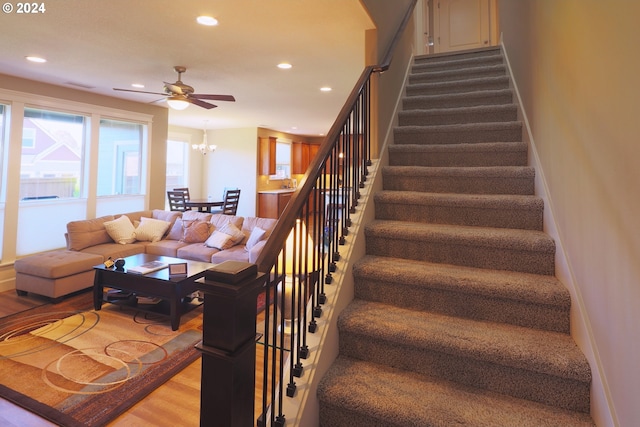 stairway featuring ceiling fan with notable chandelier and hardwood / wood-style flooring