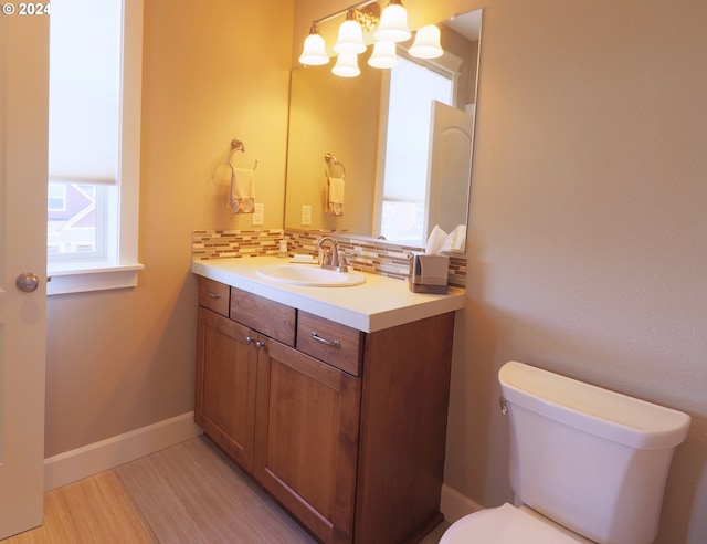 bathroom featuring vanity, toilet, and decorative backsplash