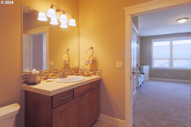 bathroom featuring vanity, toilet, and decorative backsplash