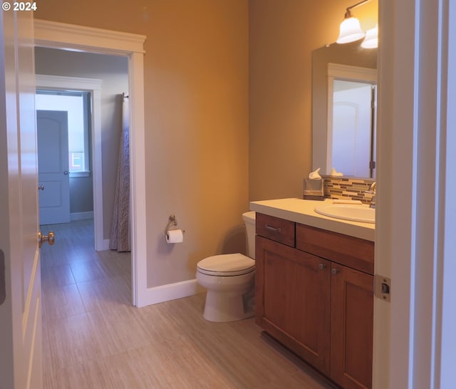 bathroom with vanity, toilet, and decorative backsplash