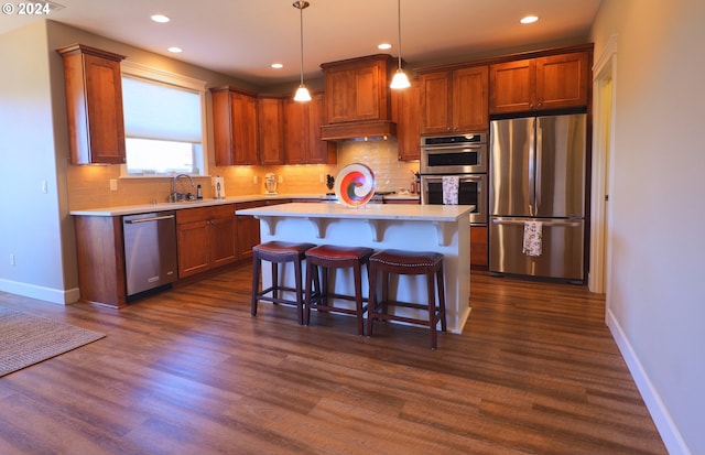 kitchen with stainless steel appliances, decorative light fixtures, dark hardwood / wood-style flooring, a breakfast bar, and a center island