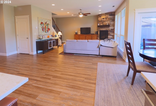 living room with a fireplace, light hardwood / wood-style floors, and ceiling fan